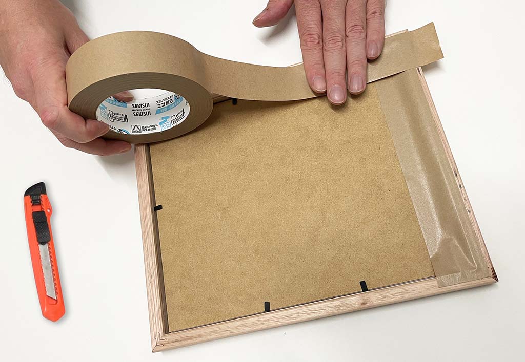 Applying framing tape to the back of a picture frame