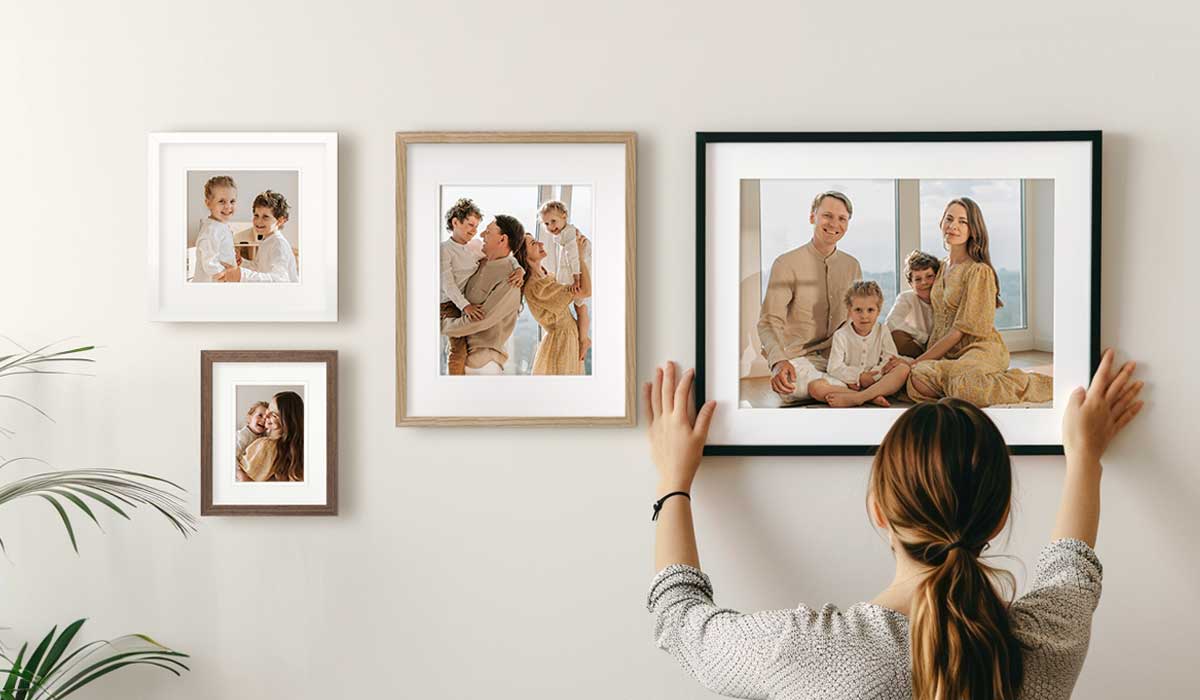 Woman hanging framed photos on wall