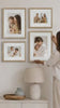 Lady hanging gallery wall frame set of timber frames with family photos. 